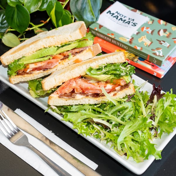 Vegan BLT sandwich with avocado, tomato, and lettuce, served with a side salad at Not Ya Mamas Cafe.