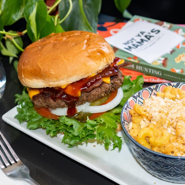 A BBQ bacon cheeseburger with lettuce, tomato, onion, and pickles, served with a side of mac and cheese.